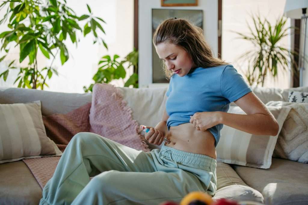 Diabetic woman injecting insulin into her abdomen.